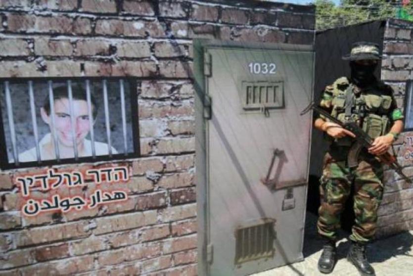 عنصر من القسام يقب الى جانب مجسم وضعت عليه صورة الضابط الاسير هدار جولدن