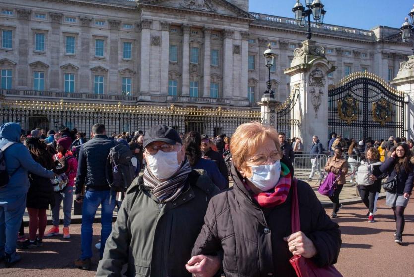 مسنان يرتديان أقنعة واقية أمام قصر باكنغهام بلندن