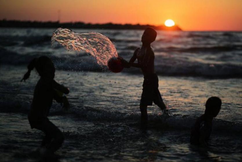 أطفال يلعبون بالماء للهرب من حرارة الجو